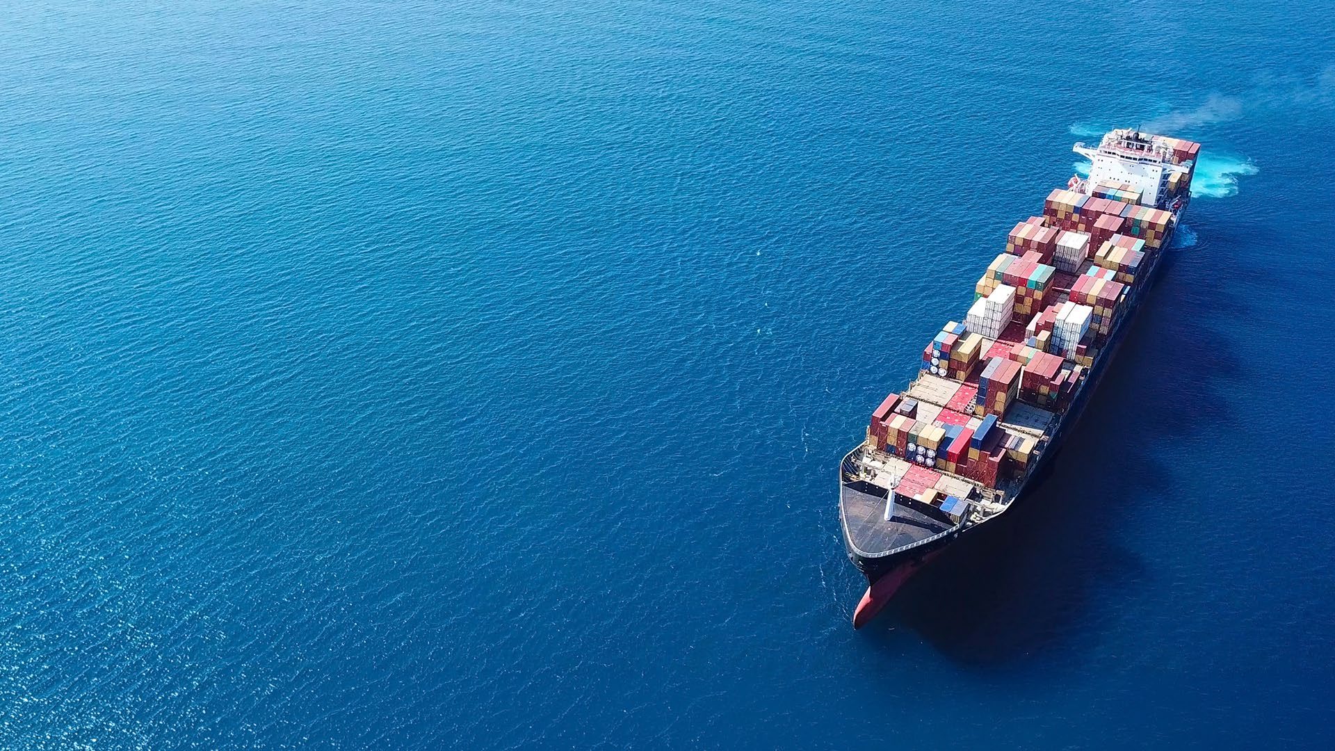 Aerial view of a loaded container ship under way on deep blue water